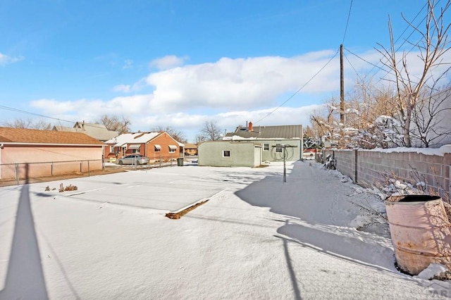 yard layered in snow with a residential view and fence