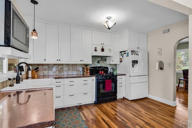 1215 Greenwood Ave, Canon City, CO 81212 - kitchen featuring white fridge with ice dispenser, gas stove, stainless steel microwave, arched walkways, and backsplash
