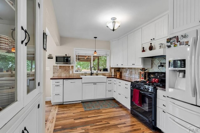 1215 Greenwood Ave, Canon City, CO 81212 - kitchen featuring white appliances, light wood-style flooring, tasteful backsplash, white cabinetry, and hanging light fixtures