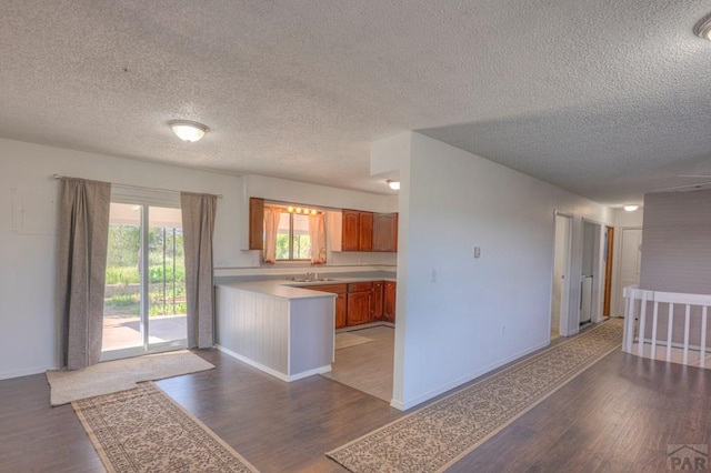2000 Comanche Dr, Walsenburg, CO 81089 - kitchen with a textured ceiling, light countertops, wood finished floors, brown cabinets, and a peninsula