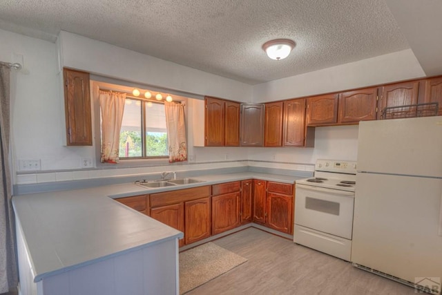 2000 Comanche Dr, Walsenburg, CO 81089 - kitchen with white appliances, a sink, a textured ceiling, a peninsula, and brown cabinets