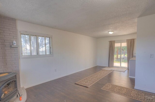 2000 Comanche Dr, Walsenburg, CO 81089 - unfurnished room with a textured ceiling, wood finished floors, a wood stove, and baseboards