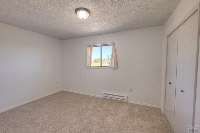 2000 Comanche Dr, Walsenburg, CO 81089 - unfurnished bedroom featuring a baseboard heating unit, carpet floors, a textured ceiling, a closet, and baseboards