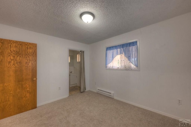2000 Comanche Dr, Walsenburg, CO 81089 - unfurnished bedroom with baseboard heating, carpet floors, a textured ceiling, connected bathroom, and baseboards