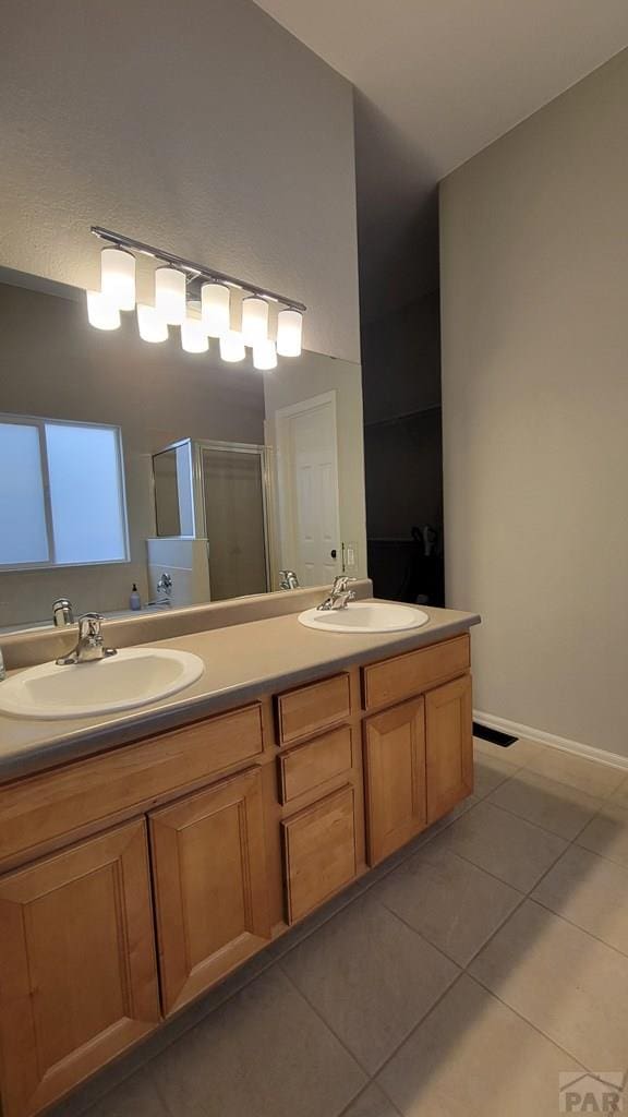 full bath with a sink, a stall shower, double vanity, and tile patterned flooring