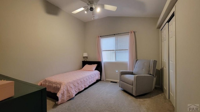 bedroom with visible vents, light colored carpet, lofted ceiling, a closet, and a ceiling fan