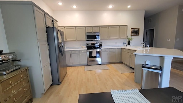 kitchen featuring appliances with stainless steel finishes, gray cabinetry, a peninsula, and a sink