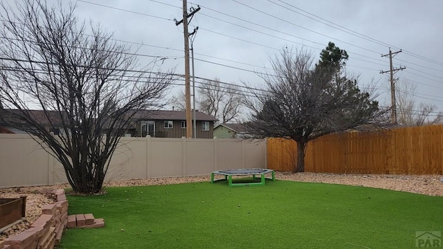 view of yard with a trampoline and a fenced backyard