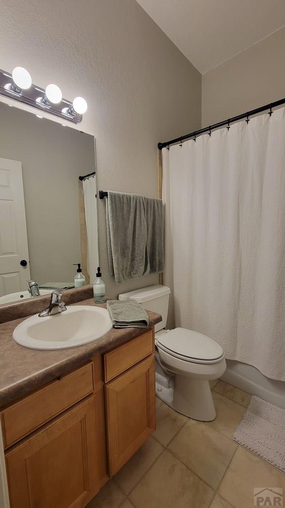 bathroom with tile patterned floors, toilet, vanity, and shower / bathtub combination with curtain