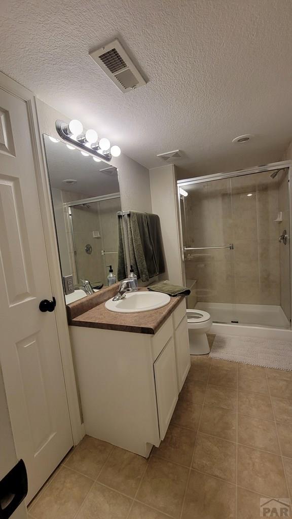 bathroom with visible vents, toilet, a stall shower, tile patterned flooring, and vanity