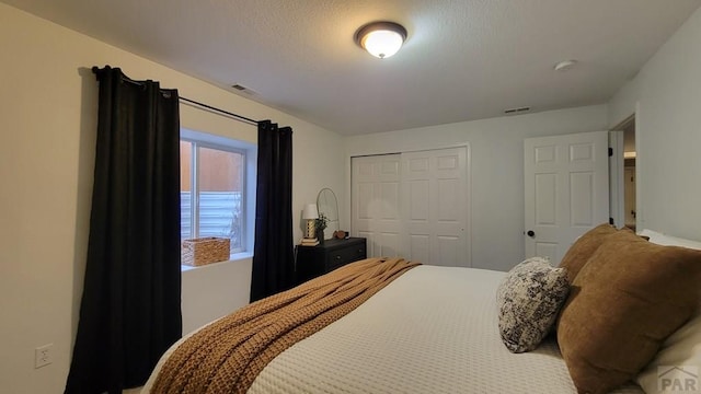 bedroom featuring a closet, visible vents, and a textured ceiling