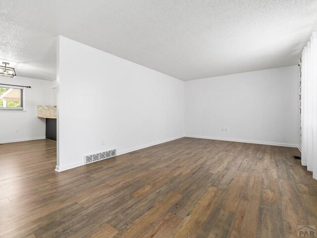 213 Starlite Dr, Pueblo, CO 81005 - unfurnished room featuring a textured ceiling, dark wood-style floors, and a chandelier