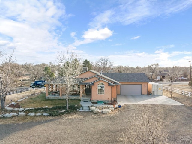 view of front of house featuring a garage, concrete driveway, fence, and stucco siding