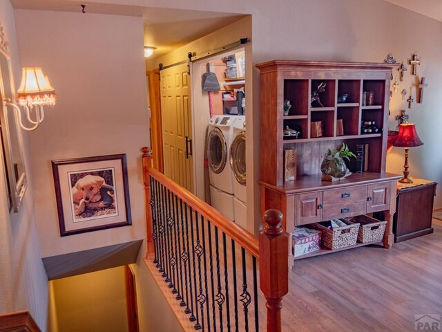 interior space with a barn door, separate washer and dryer, and wood finished floors