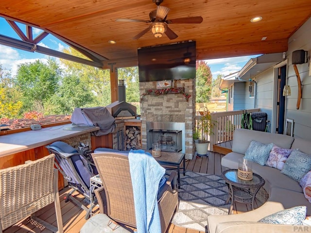 wooden deck featuring an outdoor stone fireplace and a ceiling fan