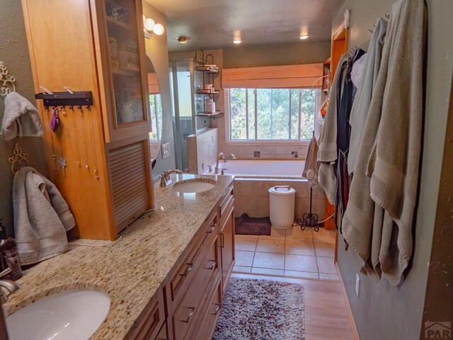 bathroom featuring tile patterned flooring, a garden tub, a sink, and double vanity