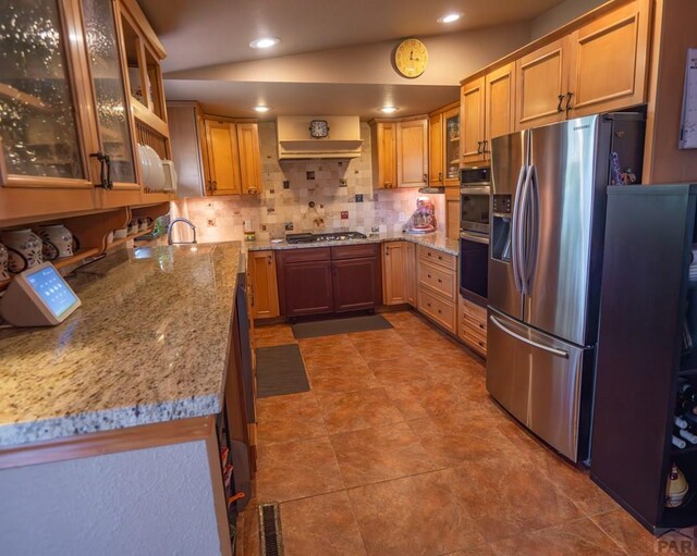 kitchen featuring recessed lighting, visible vents, appliances with stainless steel finishes, light stone countertops, and glass insert cabinets