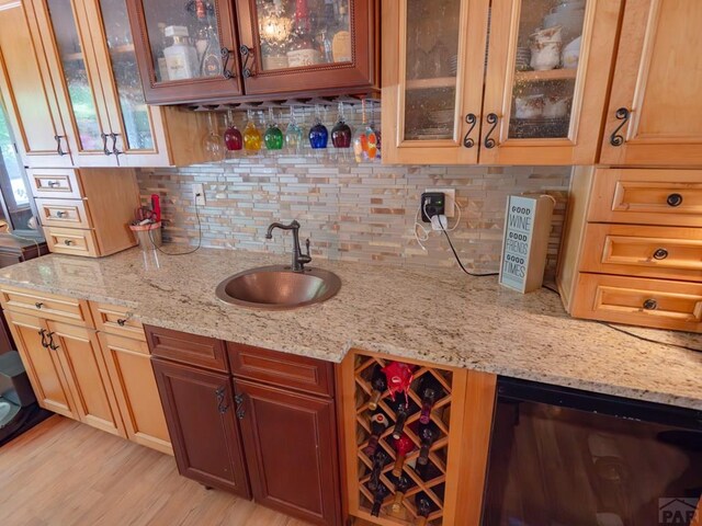 bar with tasteful backsplash, indoor wet bar, a sink, and light wood-style floors