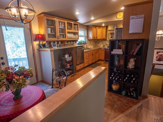 bar featuring dishwasher, lofted ceiling, decorative light fixtures, a chandelier, and a sink