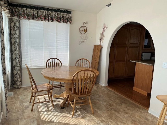 dining area featuring arched walkways, visible vents, and baseboards