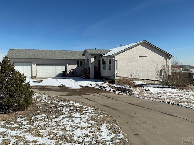 view of front of house featuring driveway, an attached garage, and stucco siding