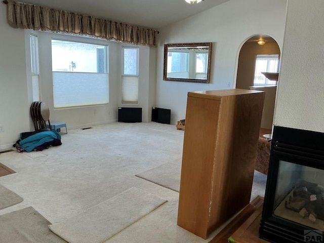 misc room with arched walkways, vaulted ceiling, and carpet flooring