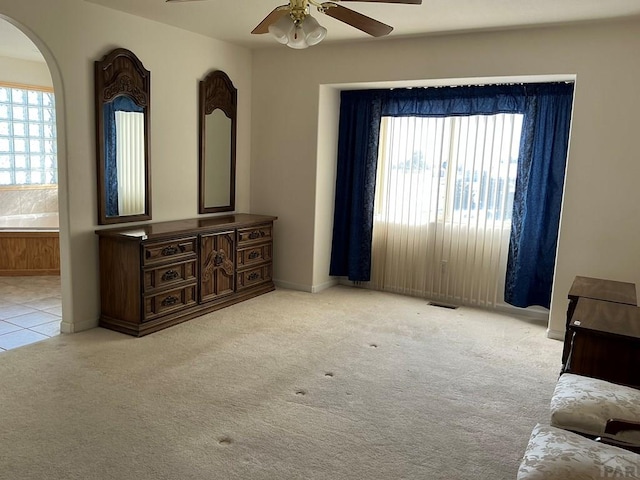 living area with a healthy amount of sunlight, ceiling fan, baseboards, and light colored carpet