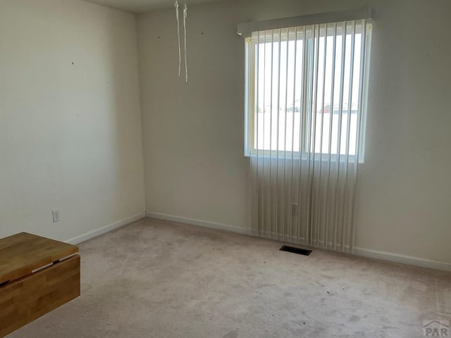 spare room with light carpet, visible vents, and baseboards