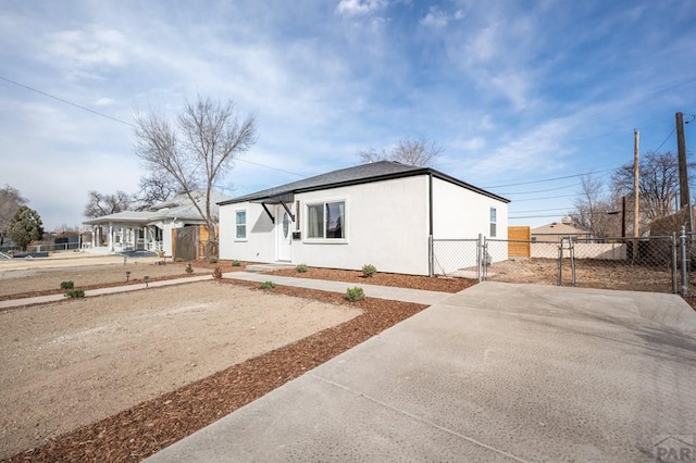 view of front facade featuring driveway, fence, and stucco siding