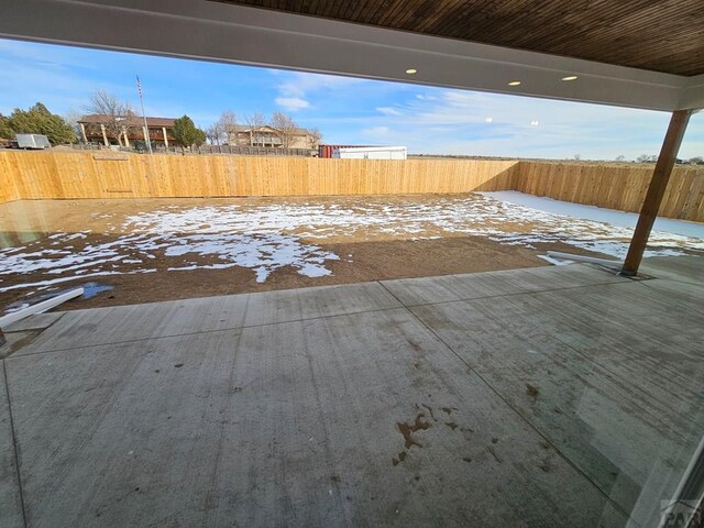 yard covered in snow featuring a patio and a fenced backyard