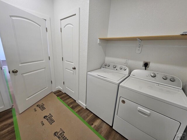 laundry area with a textured wall, laundry area, separate washer and dryer, and dark wood-style flooring