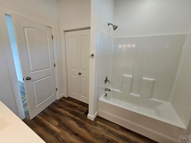 bathroom with a closet, bathing tub / shower combination, and wood finished floors