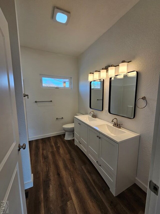 bathroom with baseboards, a sink, toilet, and wood finished floors