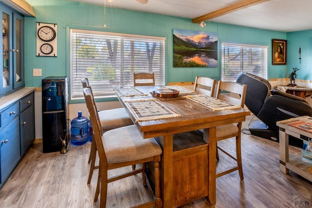 dining room featuring light wood-style floors and beamed ceiling