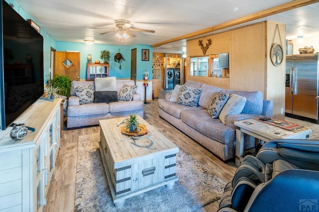 living room with light wood finished floors, washer and clothes dryer, and a ceiling fan