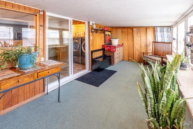 interior space with wooden walls, washing machine and dryer, and light colored carpet