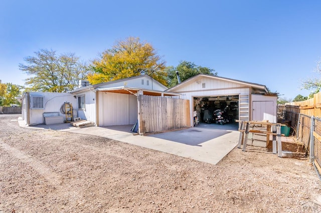 exterior space featuring a detached garage, fence, and an outdoor structure