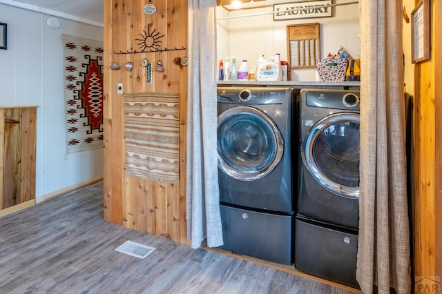 washroom with laundry area, visible vents, wood finished floors, and washing machine and clothes dryer