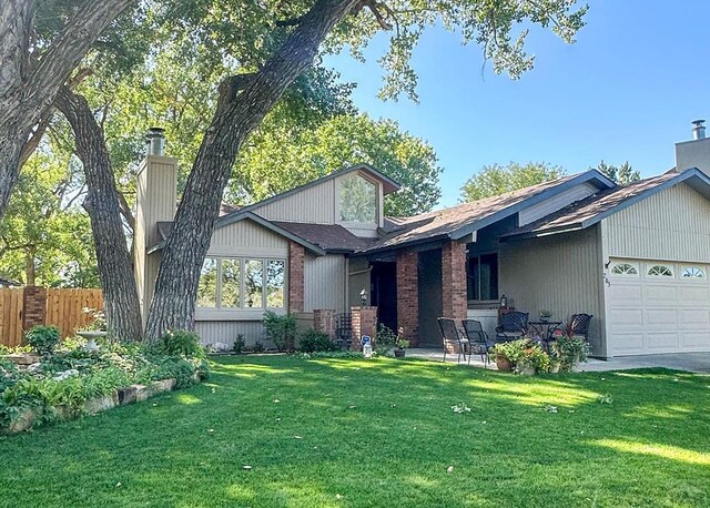 mid-century modern home featuring brick siding, a patio, an attached garage, a front yard, and fence