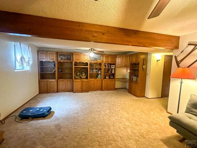 unfurnished living room with light carpet, ceiling fan, a textured ceiling, and beam ceiling