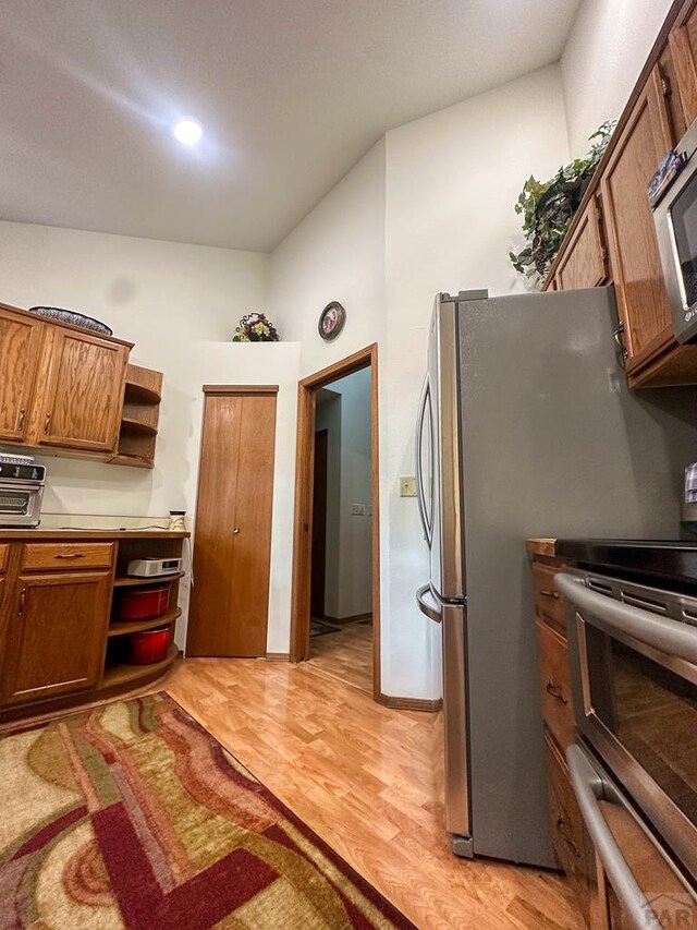 kitchen featuring open shelves, brown cabinetry, light countertops, and range