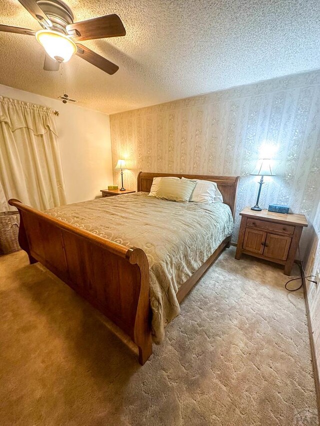 bedroom featuring wallpapered walls, carpet, a ceiling fan, and a textured ceiling