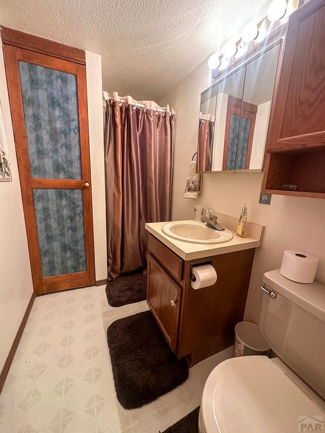 full bathroom featuring a textured ceiling, toilet, a shower with shower curtain, vanity, and baseboards