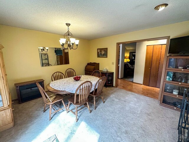 dining room featuring light colored carpet, a textured ceiling, and an inviting chandelier