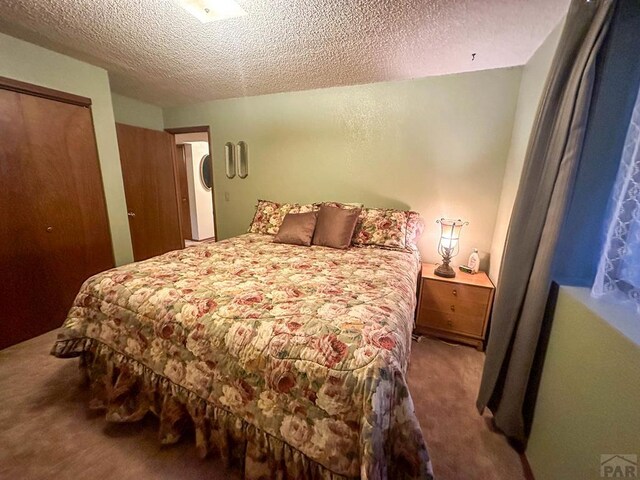 bedroom featuring a closet, a textured ceiling, and carpet flooring