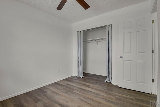 unfurnished bedroom with a closet, dark wood-type flooring, a ceiling fan, a textured ceiling, and baseboards