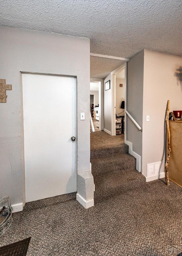 stairs with carpet floors, a textured ceiling, and baseboards