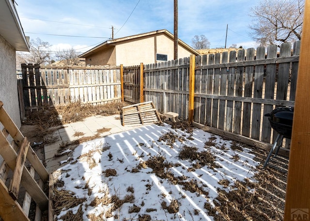 snowy yard featuring a fenced backyard