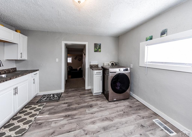 laundry room with washer / clothes dryer, visible vents, baseboards, cabinet space, and light wood finished floors