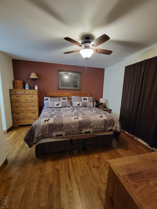 bedroom with light wood-style flooring, ceiling fan, and a textured ceiling